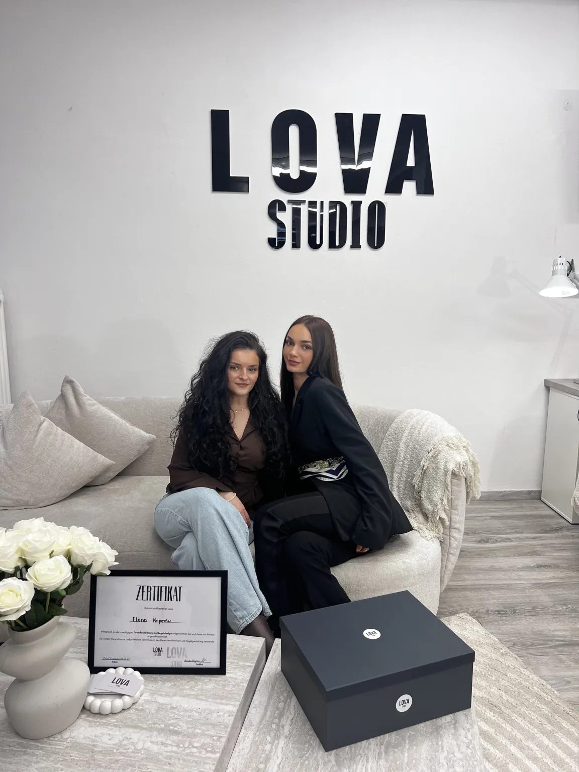Ariola und ihre Schülerin mit dem Zertifikat unter dem LOVA-STUDIO-Schriftzug