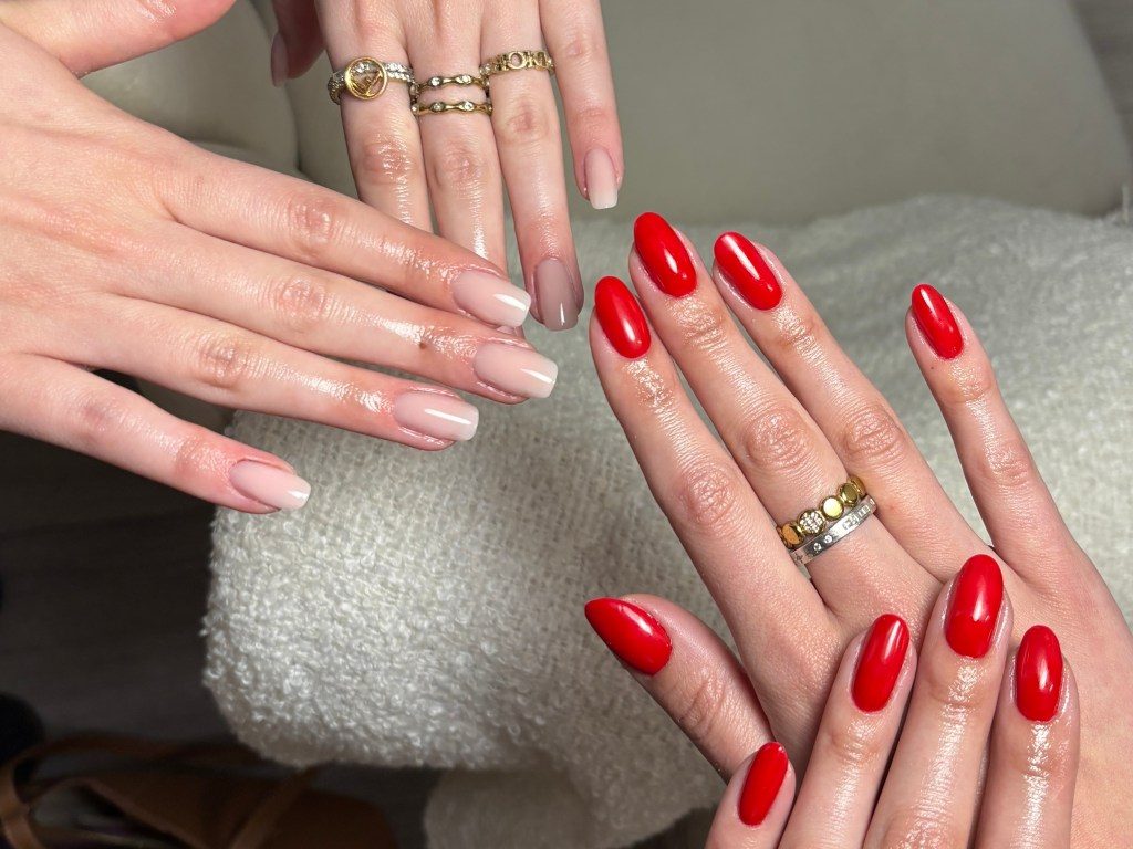 Zwei Hände mit Modellage, links milchiges Nude, rechts kräftiges Rot